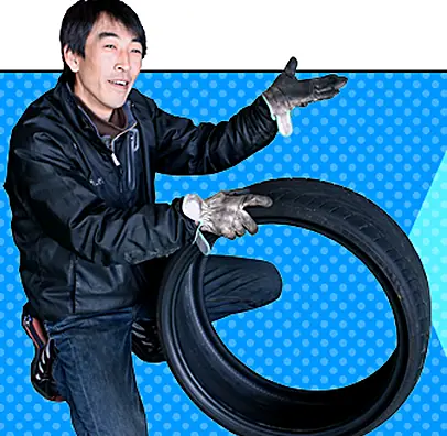 タイヤを手に、査定を案内するスタッフ